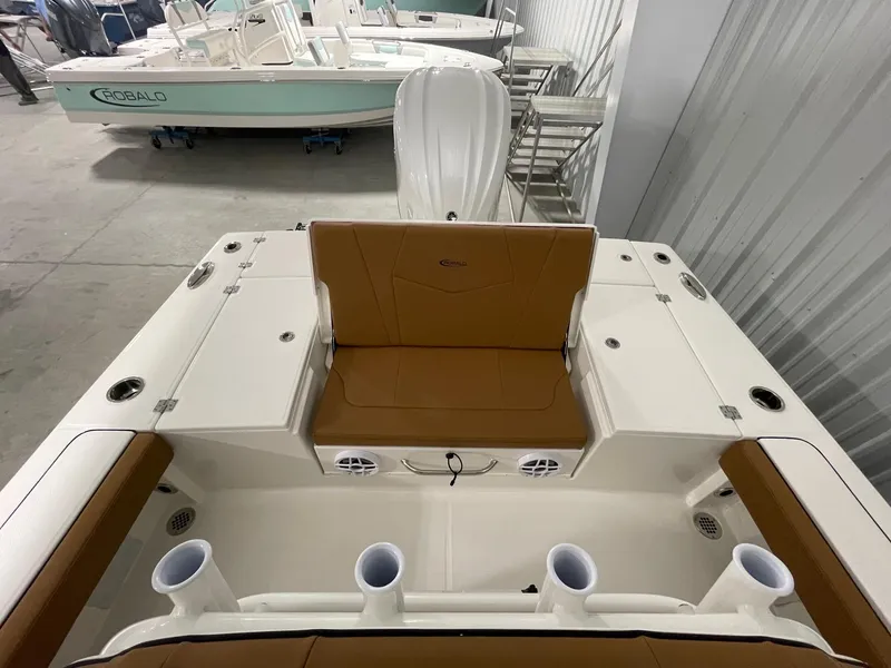 Slide: The Image of 2025 Robalo 246 Cayman boat interior with tan seating and rod holders in a showroom. - 6