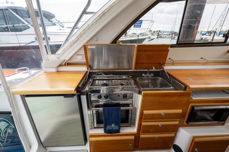 Slide: The Image of 2017 Cutwater C-302 Sport Coupe kitchen with stove, sink, and wooden cabinetry. - 16