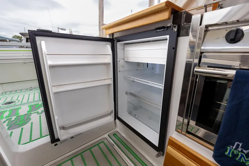 Slide: The Image of Open refrigerator inside 2017 Cutwater C-302 Sport Coupe boat, showcasing interior storage space. - 17