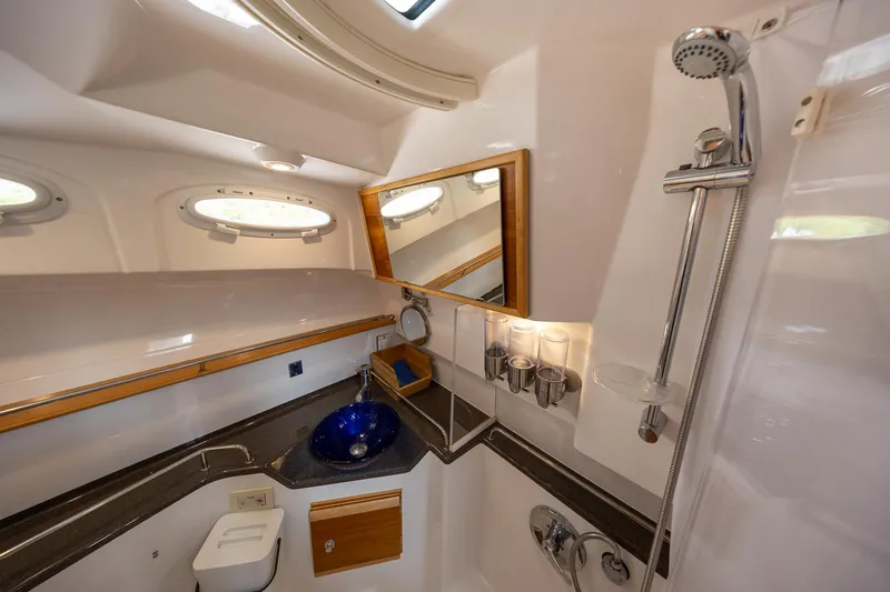 Slide: The Image of 2017 Cutwater C-302 Sport Coupe bathroom with shower, blue sink, and porthole windows. - 29