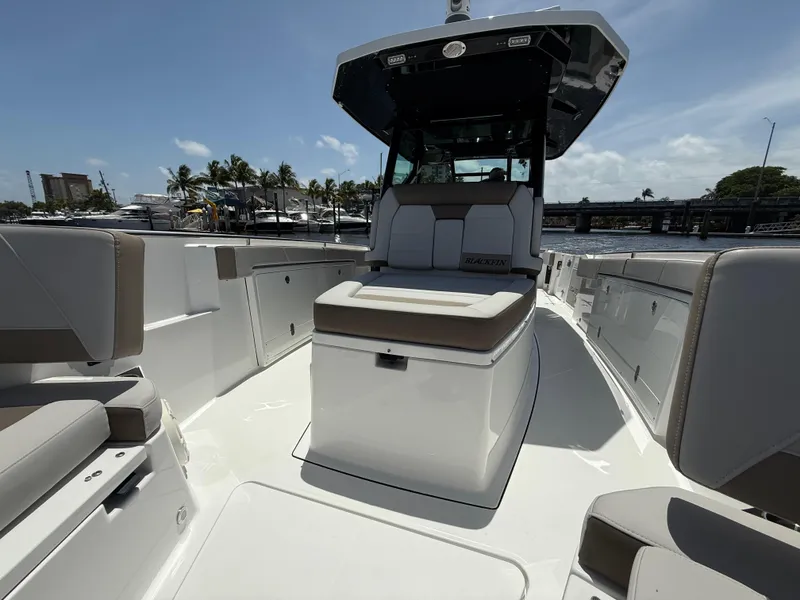 Slide: The Image of 2020 Blackfin 332 CC boat interior with seating, docked near marina under clear sky. - 22