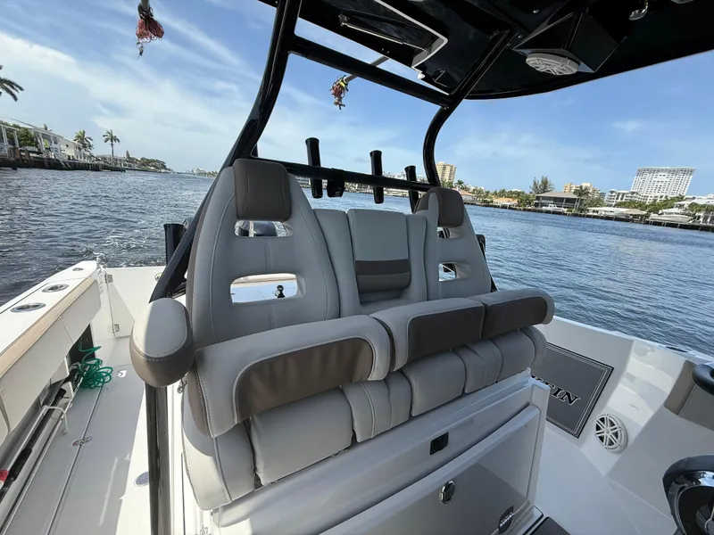 Slide: The Image of 2020 Blackfin 332 CC boat interior with plush seating, overlooking a scenic waterfront. - 9