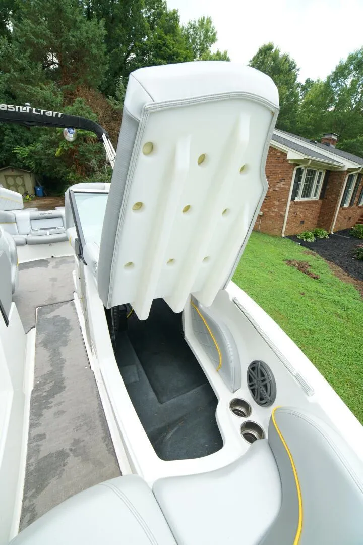 Slide: The Image of 2014 MasterCraft X-25 boat interior with open storage compartment, cup holders, and speaker. - 41