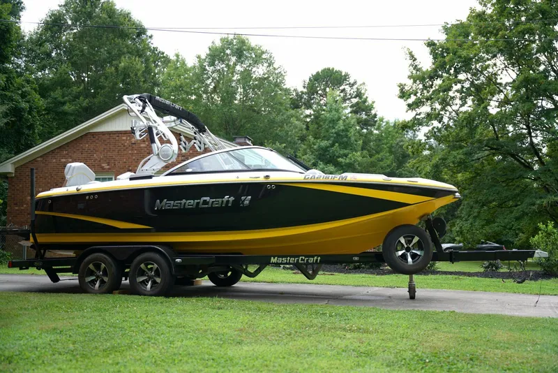 Slide: The Image of 2014 MasterCraft X-25 boat on trailer, parked in a lush green yard. - 8