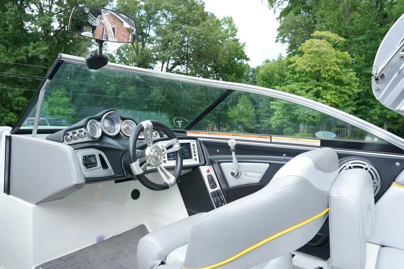 Slide: The Image of 2014 MasterCraft X-25 boat interior with steering wheel and dashboard, surrounded by lush greenery. - 12