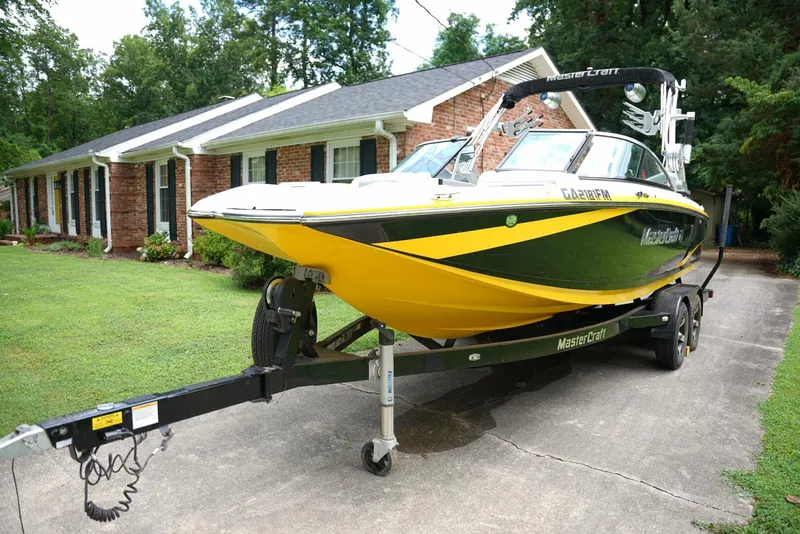 Slide: The Image of 2014 MasterCraft X-25 boat on trailer, parked in a lush green yard. - 6