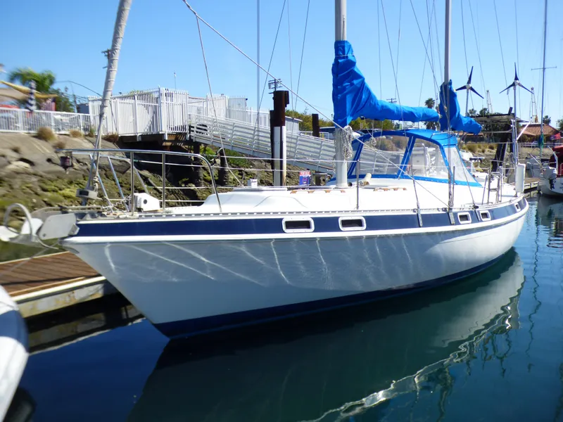 The Image of 1981 Morgan 416 Out Island sailboat docked in a marina, featuring blue accents and clear skies. - 0