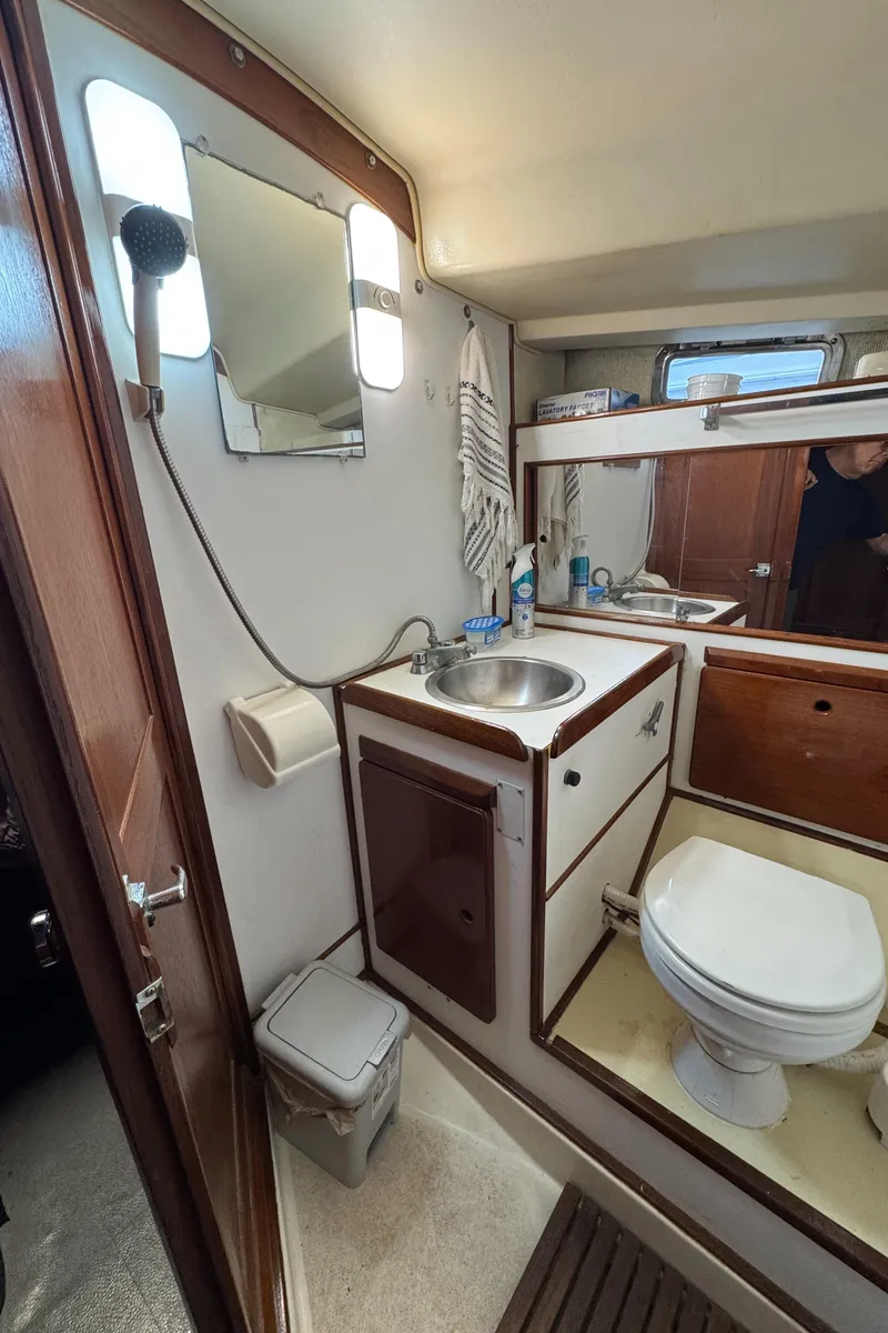 Slide: The Image of 1981 Morgan 416 Out Island yacht bathroom with sink, toilet, mirror, and wooden accents. - 17