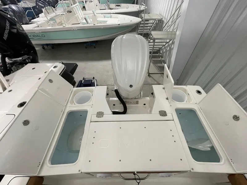 Slide: The Image of 2025 Robalo 246 Cayman boat interior with storage compartments and engine in a showroom. - 15