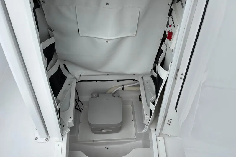 Slide: The Image of 2025 Wellcraft 243 Fisherman boat interior with storage compartments and portable toilet. - 17