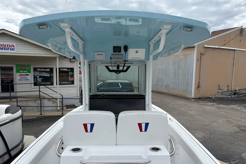 Slide: The Image of 2025 Wellcraft 243 Fisherman boat with blue T-top, parked near marine shop. - 5