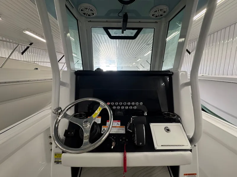 Slide: The Image of 2025 Wellcraft 243 Fisherman boat console with steering wheel and controls in a bright showroom. - 8