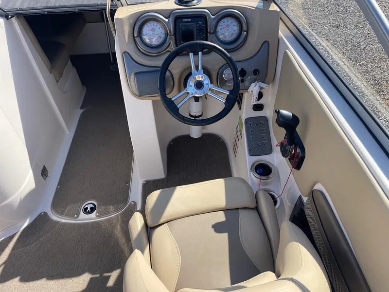 Slide: The Image of 2014 Starcraft Crossover 250 SCX IO boat cockpit with steering wheel and control panel. - 2