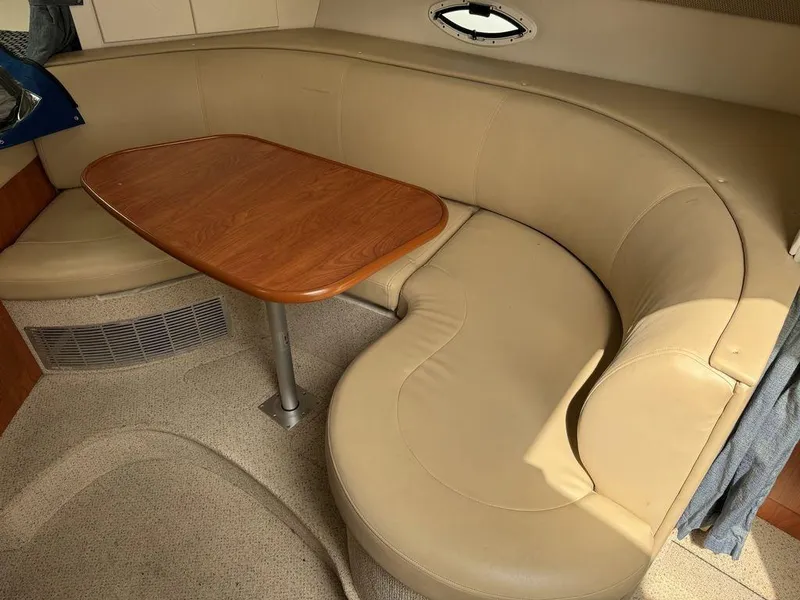 Slide: The Image of 2005 Bayliner 305 interior with beige leather seating and wooden table. - 16