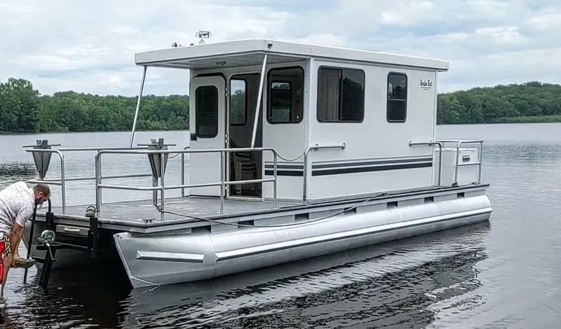 The Image of Custom 2010 River Time Houseboat on a calm lake with lush green trees. - 0