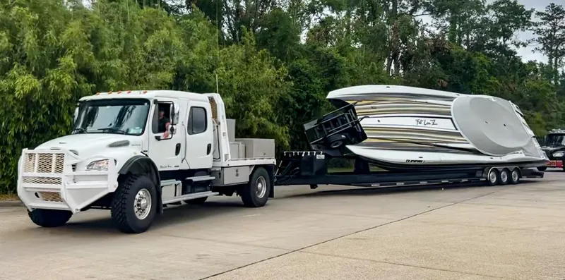 Slide: The Image of A white truck towing a large MTI 48 boat on a trailer, surrounded by greenery. - 11