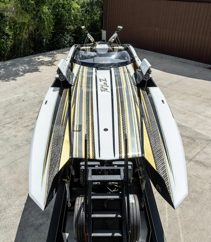 Slide: The Image of 2017 MTI 48 powerboat with sleek black and gold design on a trailer. - 14