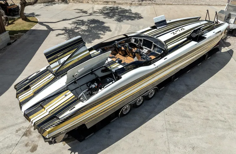 Slide: The Image of 2017 MTI 48 speedboat with sleek design and vibrant stripes, parked on concrete. - 15