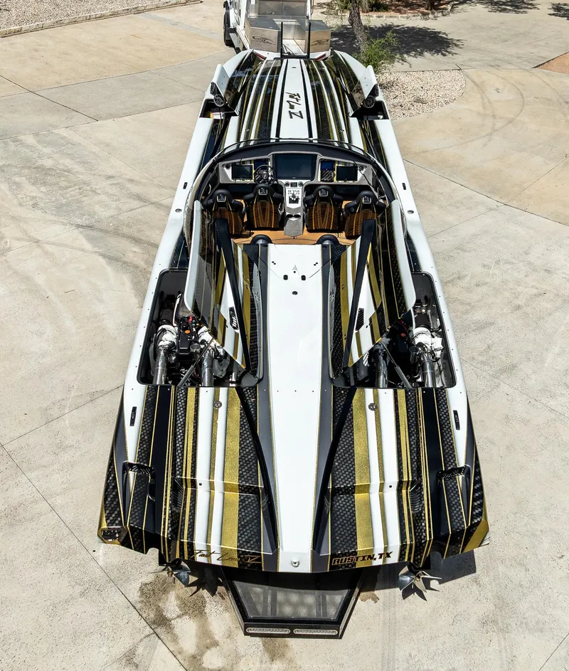 Slide: The Image of 2017 MTI 48 speedboat with sleek black and gold design, parked on concrete surface. - 16