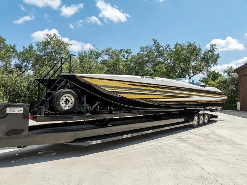 Slide: The Image of 2017 MTI 48 speedboat on trailer, featuring sleek black and gold design, parked outdoors. - 18