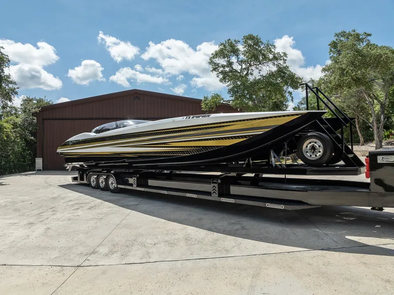 Slide: The Image of 2017 MTI 48 speedboat on trailer, parked outdoors under clear blue sky. - 19