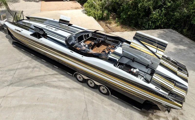 Slide: The Image of 2017 MTI 48 speedboat with sleek design and vibrant stripes, parked on concrete. - 2