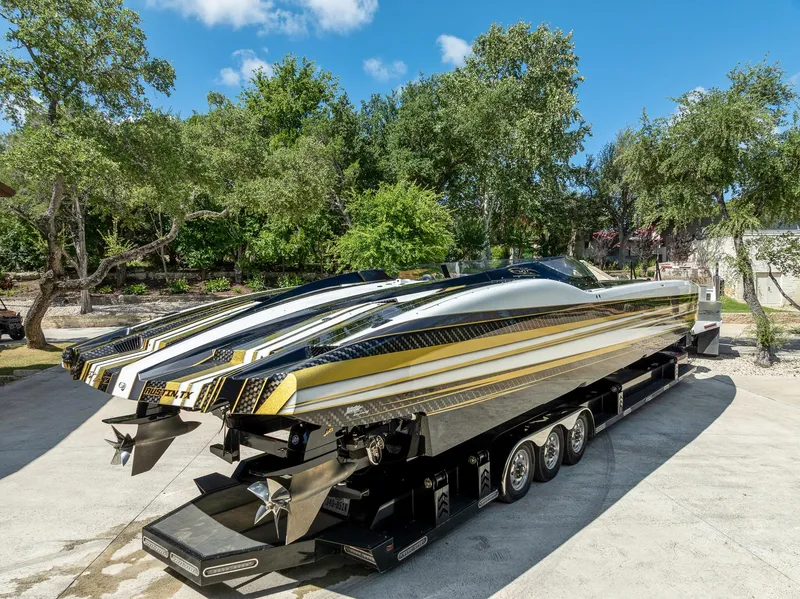 Slide: The Image of 2017 MTI 48 speedboat on trailer, sleek design, parked outdoors with trees in background. - 27