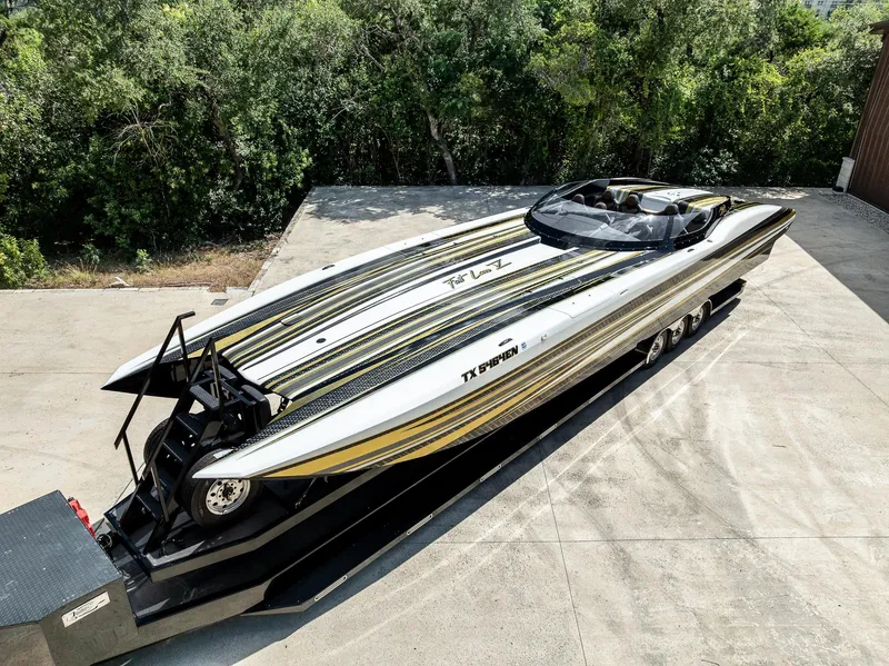 Slide: The Image of 2017 MTI 48 speedboat on trailer, featuring sleek design and vibrant stripes, parked outdoors. - 31