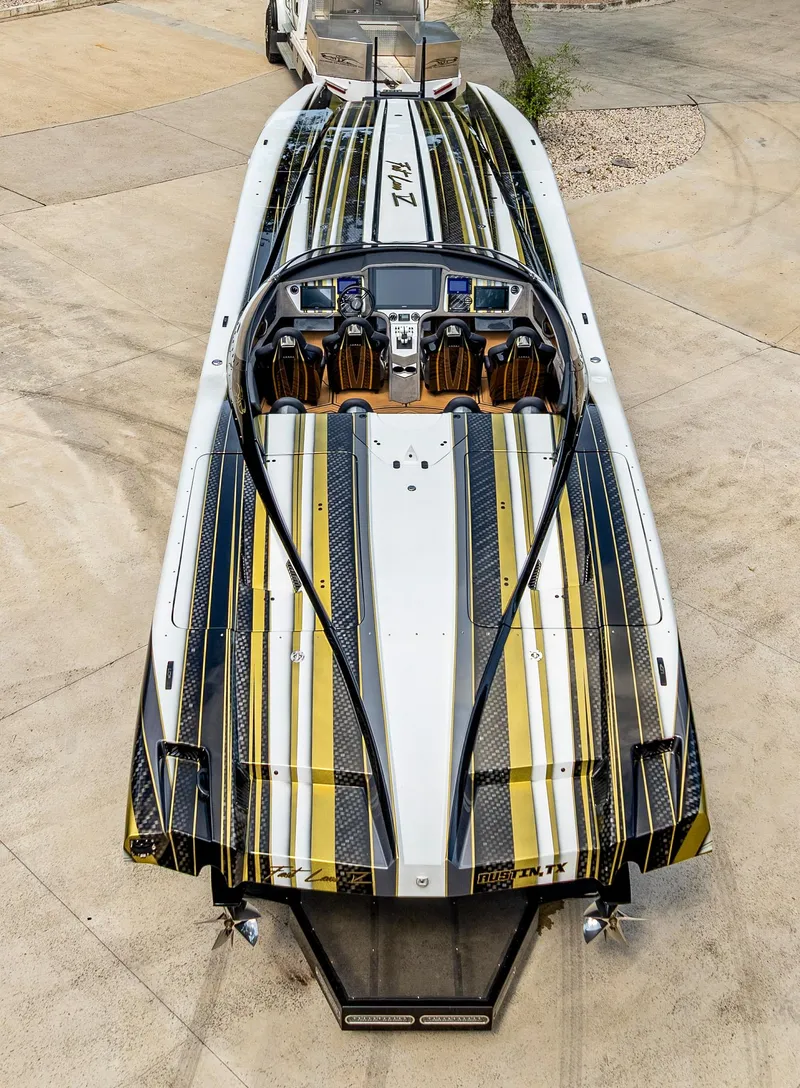 Slide: The Image of 2017 MTI 48 speedboat with sleek black and gold design, parked on concrete. - 37