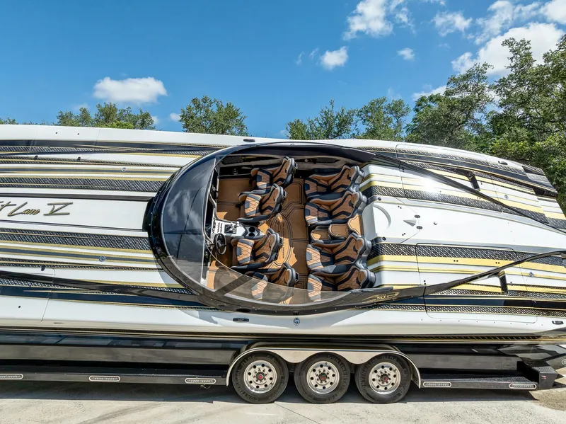 Slide: The Image of 2017 MTI 48 speedboat with sleek design and multiple seats, parked on a trailer under a clear sky. - 4