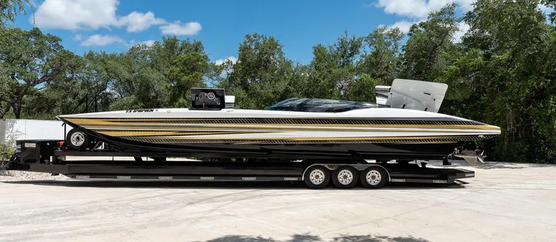 Slide: The Image of 2017 MTI 48 speedboat on trailer, sleek design, parked outdoors, surrounded by trees and blue sky. - 42