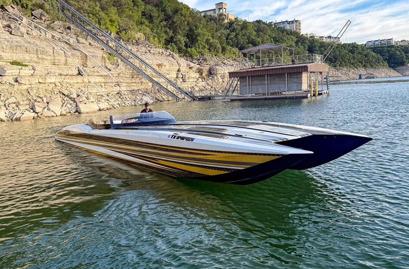 Slide: The Image of 2017 MTI 48 speedboat on a scenic lake with rocky shoreline and dock. - 8