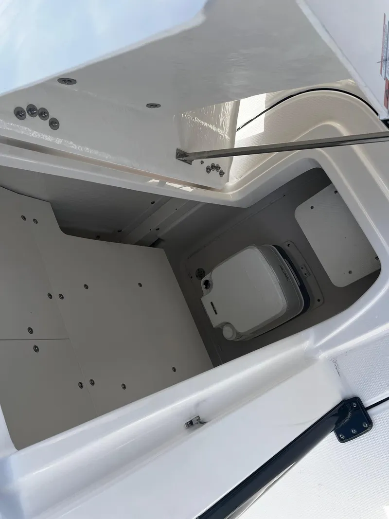 Slide: The Image of 2025 Robalo 246 Cayman boat interior storage compartment with portable toilet. - 15