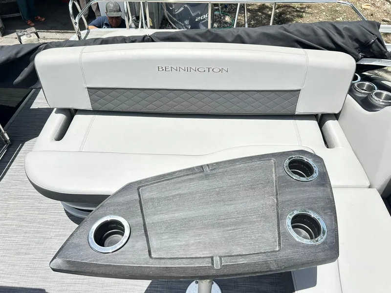 Slide: The Image of 2021 Bennington L 24 Swingback boat interior with cushioned seating and table with cup holders. - 22