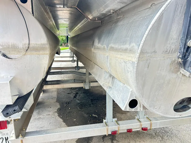 Slide: The Image of Underneath view of a 2021 Bennington L 24 Swingback pontoon boat on a trailer. - 32