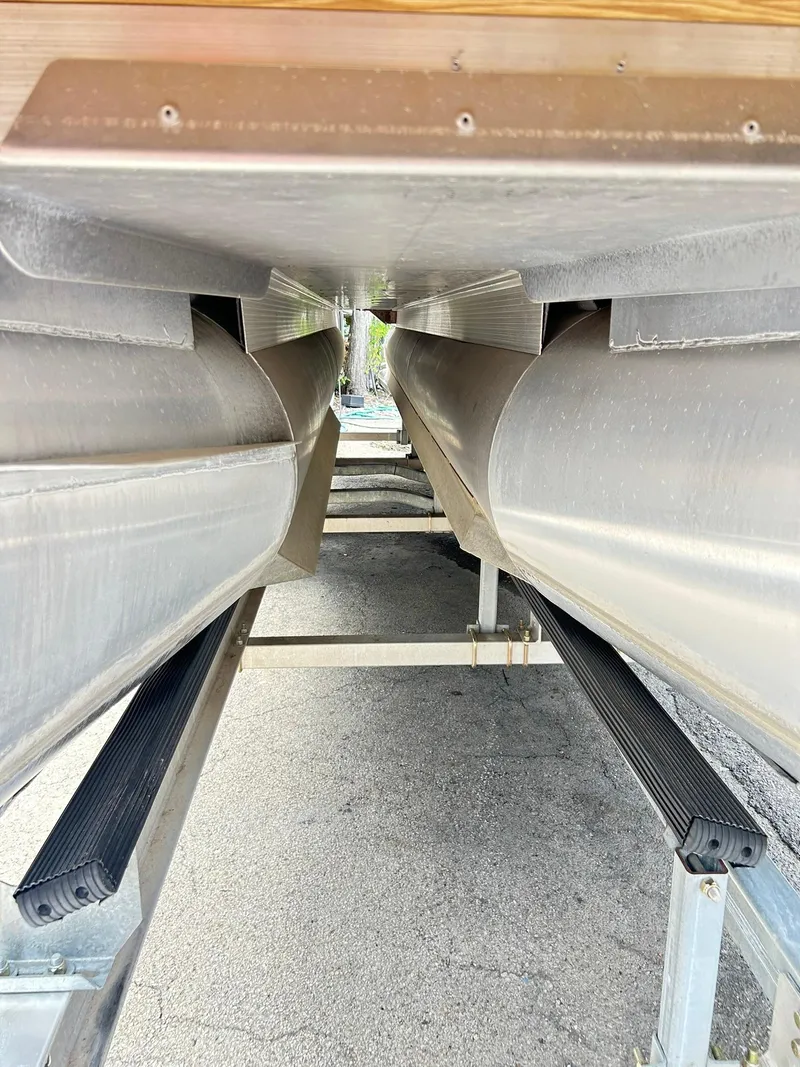 Slide: The Image of Underneath view of a 2021 Bennington L 24 Swingback pontoon boat on a trailer. - 34