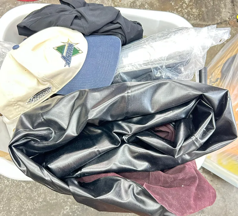 Slide: The Image of A pile of assorted clothing and a cap in a container. - 47