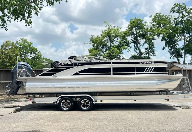 Slide: The Image of 2021 Bennington L 24 Swingback pontoon boat on trailer, parked outdoors. - 9