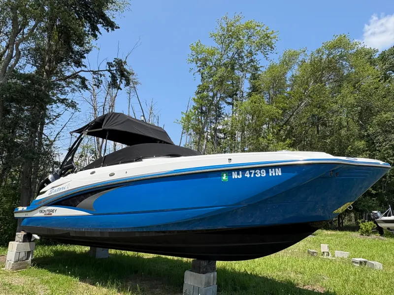 The Image of Blue 2020 Monterey M65 boat on blocks, surrounded by trees under a clear sky. - 0
