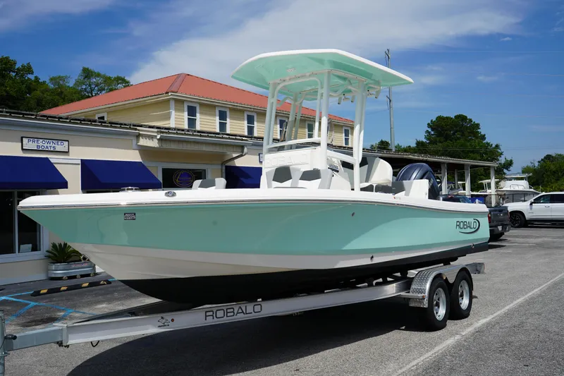 The Image of 2024 Robalo 226 Cayman boat on trailer, parked outside a dealership. - 0