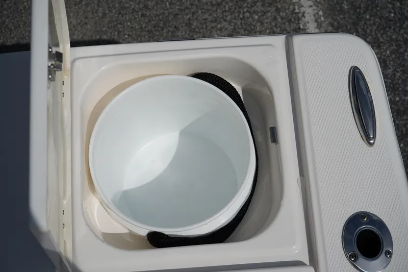 Slide: The Image of 2024 Robalo 226 Cayman boat storage compartment with bucket and rope. - 13