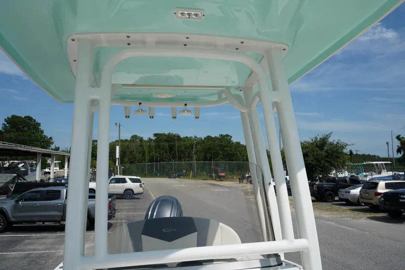 Slide: The Image of 2024 Robalo 226 Cayman boat with T-top, parked in a marina under clear skies. - 35