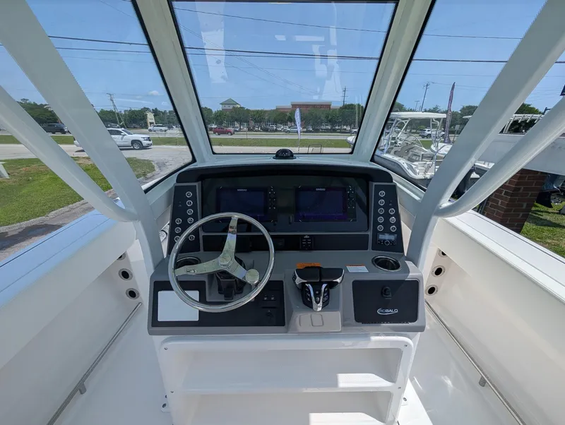 Slide: The Image of 2025 Robalo R250 Center Console boat dashboard with steering wheel and navigation screens. - 10