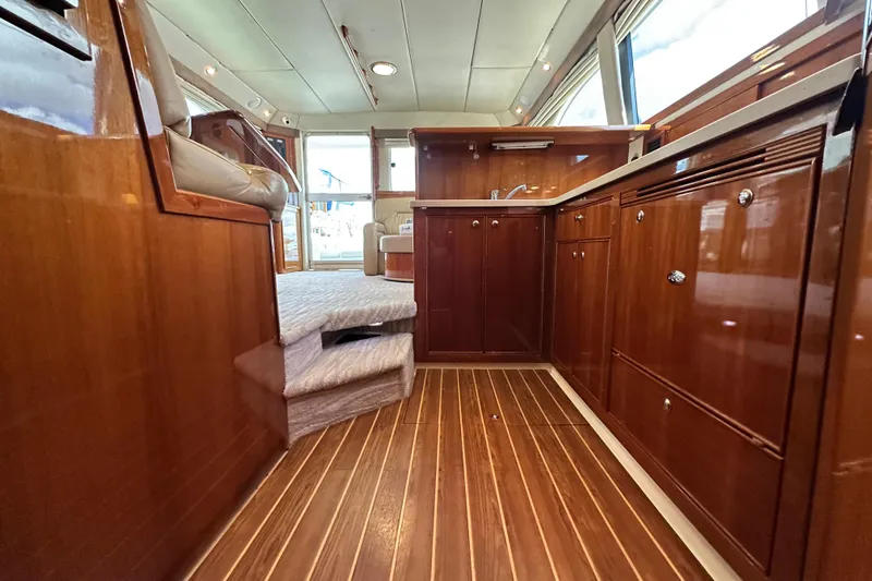 Slide: The Image of Luxurious 2005 Riviera 47 Open Flybridge interior with polished wood cabinetry and flooring. - 100