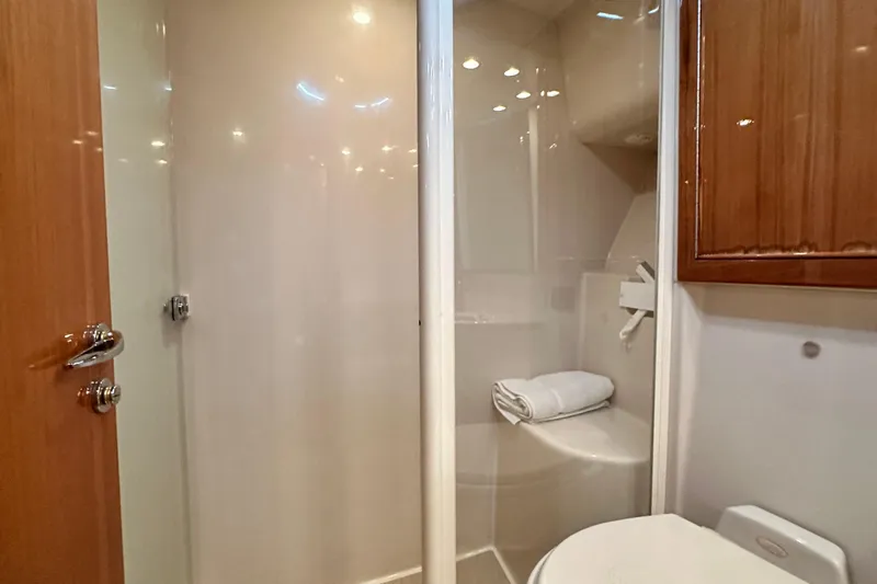 Slide: The Image of Bathroom interior of 2005 Riviera 47 Open Flybridge yacht, featuring shower and wooden cabinetry. - 122