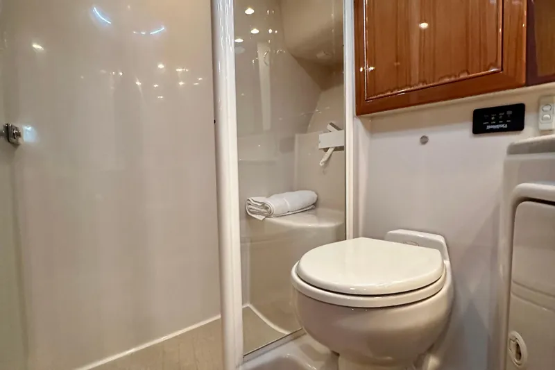 Slide: The Image of 2005 Riviera 47 Open Flybridge bathroom with shower, toilet, and wooden cabinetry. - 125
