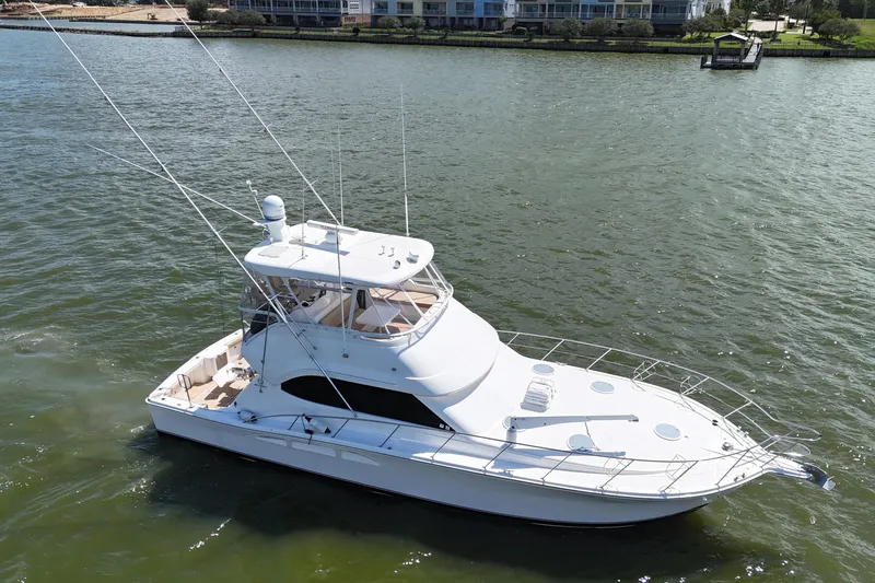 Slide: The Image of 2005 Riviera 47 Open Flybridge yacht on calm water near shoreline. - 2