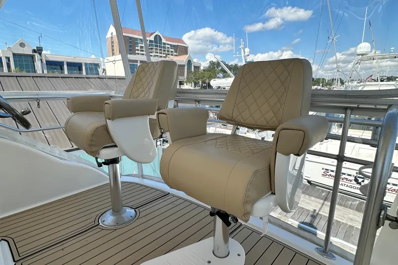 Slide: The Image of 2005 Riviera 47 Open Flybridge helm chairs with quilted upholstery on a sunny day. - 23