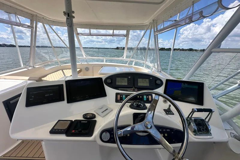 Slide: The Image of 2005 Riviera 47 Open Flybridge helm with navigation screens, steering wheel, and ocean view. - 26