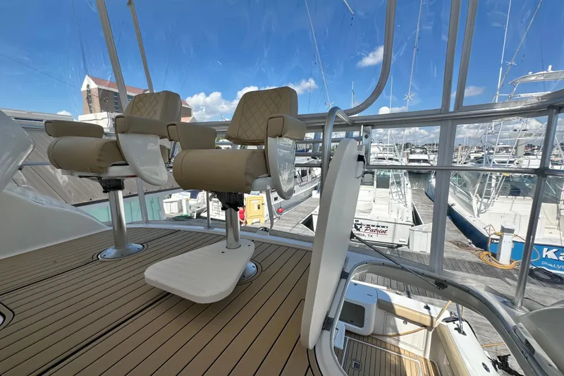 Slide: The Image of 2005 Riviera 47 Open Flybridge with helm chairs, marina view, and clear skies. - 31